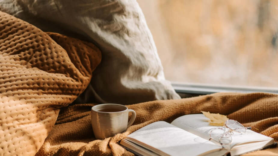 Couverture dans les teintes jaunes et beige, avec un livre ouvert et une tasse de couleur brune de café noir